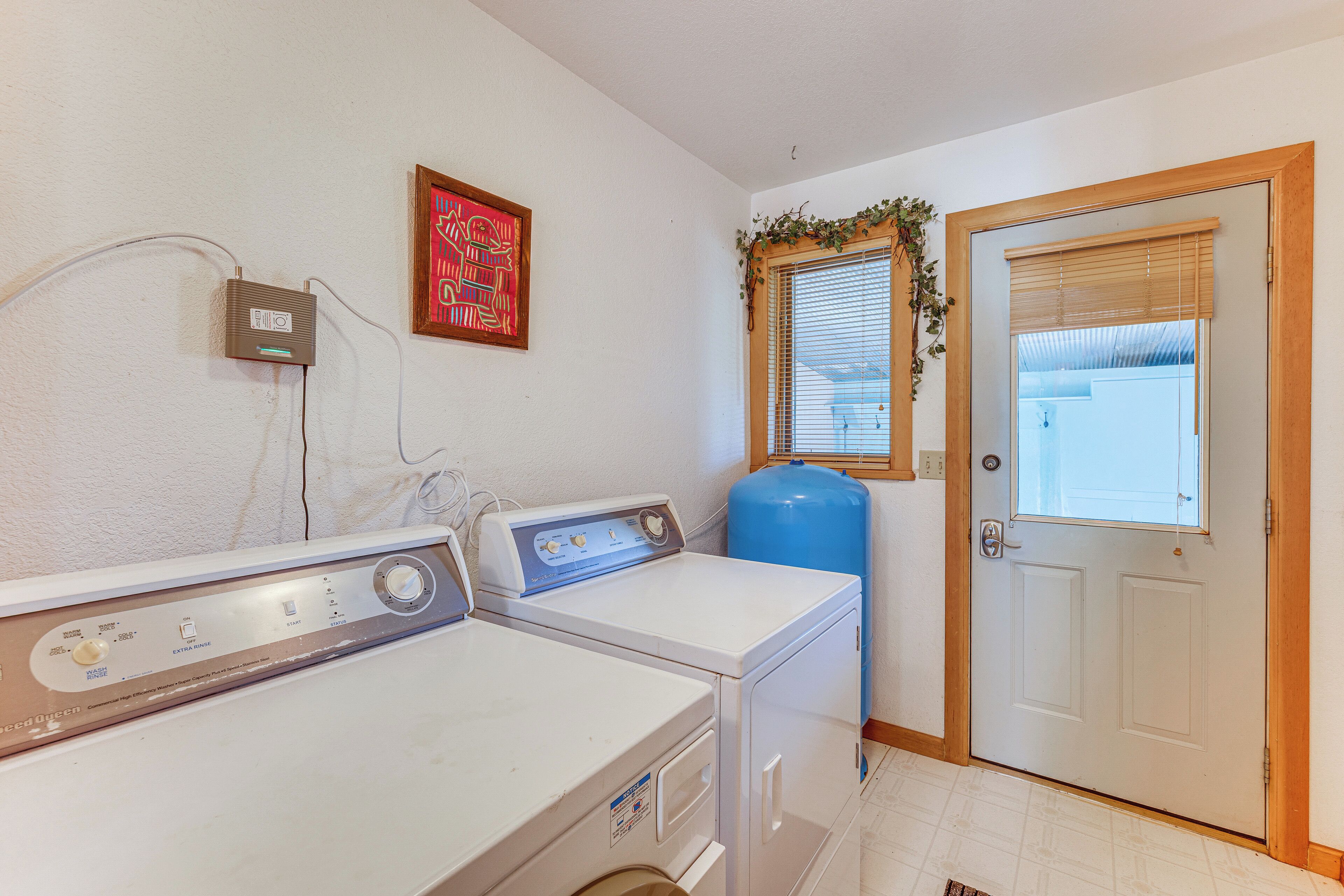 A laundry room with two front-loading washers and a blue water heater.