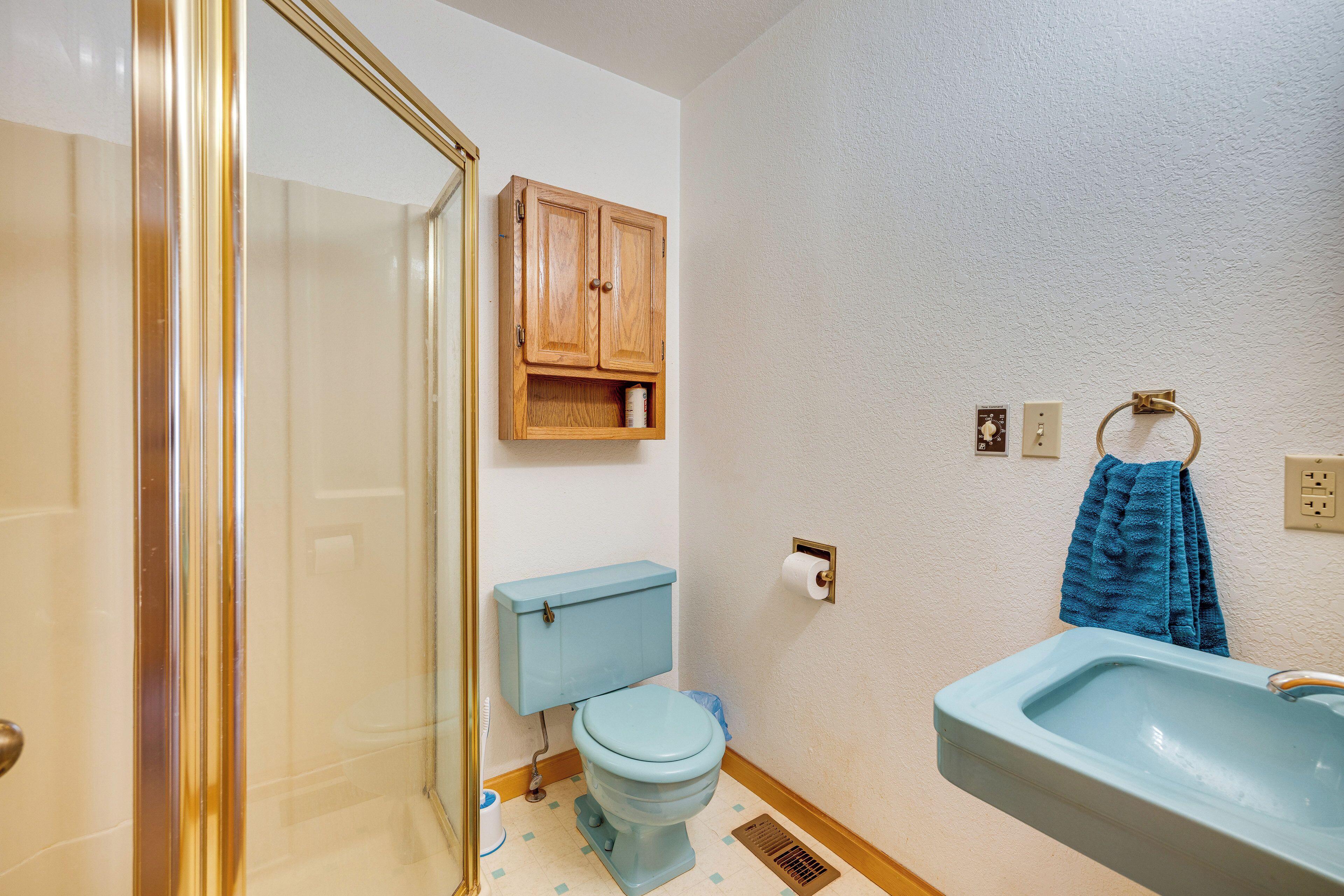 A bathroom with a toilet, sink, and cabinet.