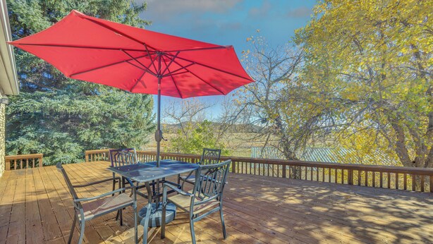 A wooden deck with a table and chairs, a red umbrella, and a view of trees and a body of water. - Mtn-view Colorado Haven! 32 Mi to Royal Gorge Park (Cotopaxi)