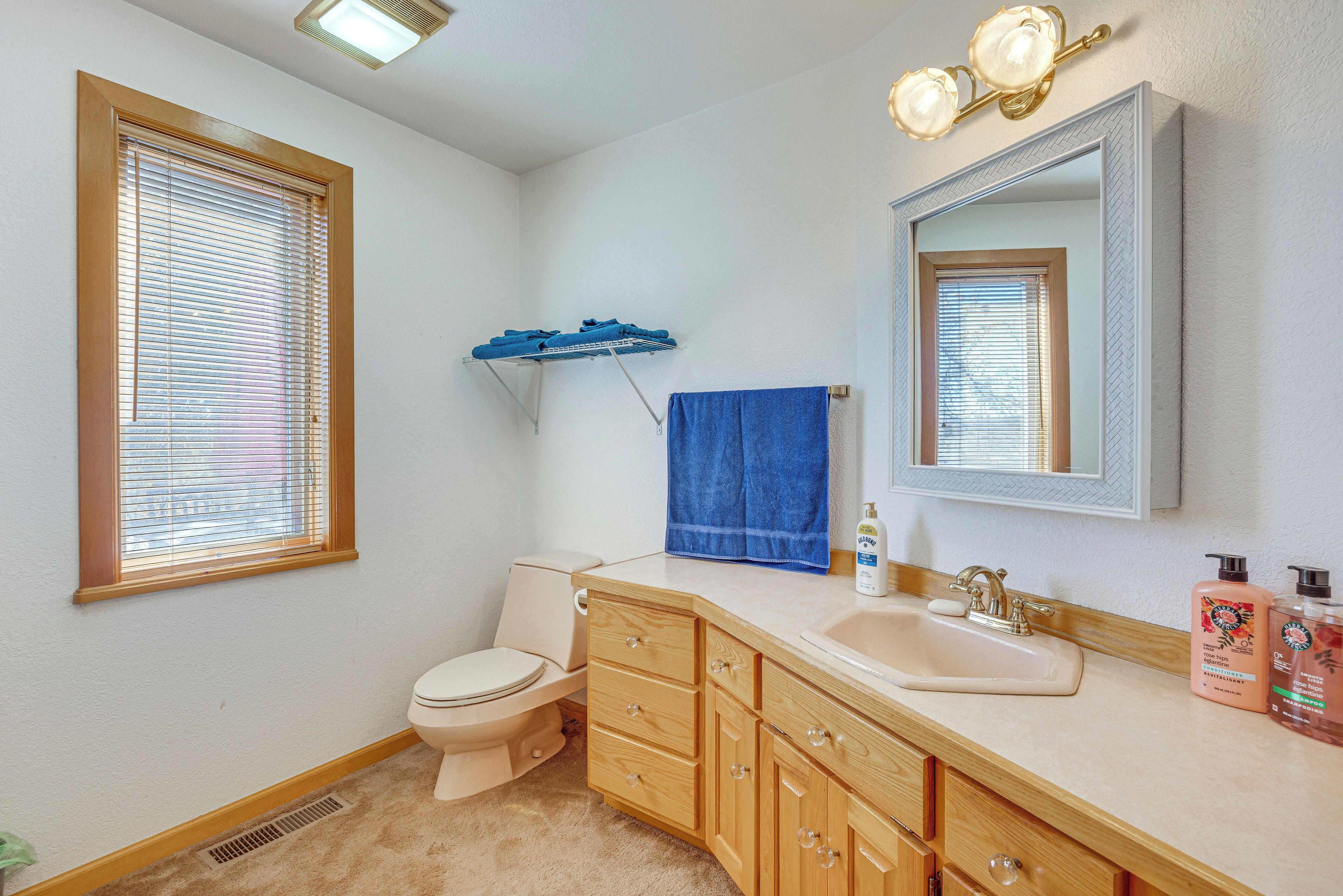 A bathroom with a toilet, sink, vanity, and a mirror.