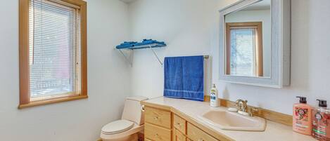 A bathroom with a toilet, sink, vanity, and a mirror.
