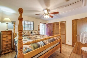 A bedroom with a wooden four-poster bed, a ceiling fan, a dresser, and a window with blinds. - Fisherman's Paradise! Lake Talquin Townhome (Quincy)