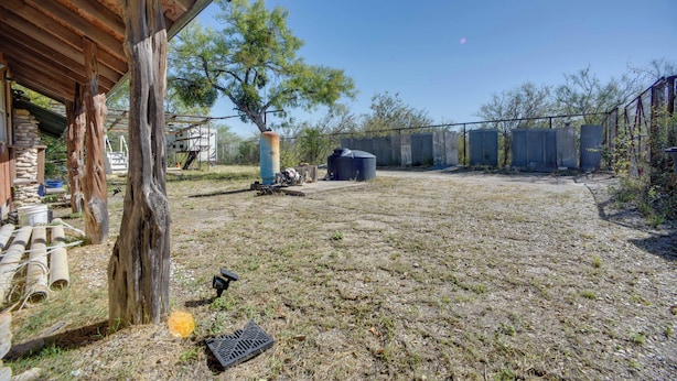 An outdoor area with a wooden structure, a tree, and a fenced yard.