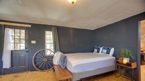A bedroom with a bed, a wooden bench, a large window, and a door.