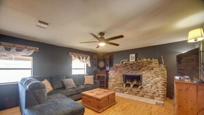 A living room with a sofa, a wooden coffee table, a stone fireplace, and a ceiling fan.