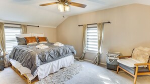 Un dormitorio con cama, una silla, una maleta y un ventilador de techo.