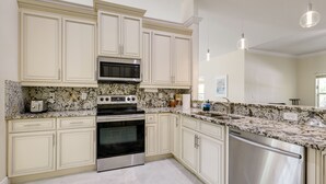 Una cocina con gabinetes blancos, un horno de acero inoxidable, un microondas y una encimera de granito.