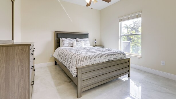 Un dormitorio con cama, cabecera de madera, mesita de noche y ventilador de techo.