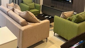 Moderni olohuone, jossa on sohvaryhmä, seinälle asennettu televisio ja ilmastointilaite.