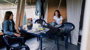 A dining area with a table set for two, a bottle of wine, and a few glasses. - Camping Gritt - De Lodge (Erpeldange-sur-Sûre)