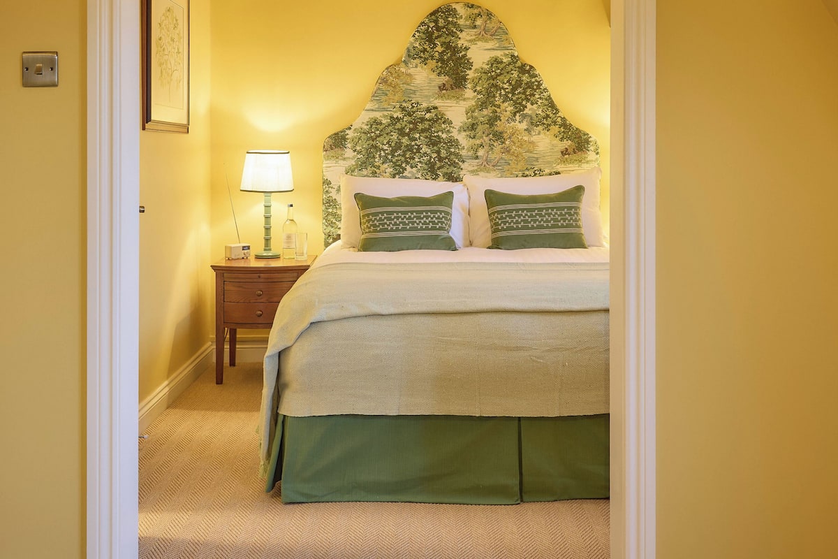 A bedroom with a bed, a nightstand, a lamp, and a wall-mounted picture.