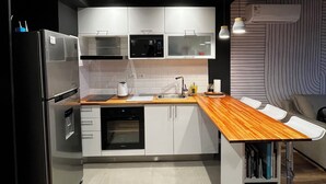 A modern kitchen with white cabinets, stainless steel appliances, and a wooden countertop. - Design apartment in historic district with river view (Montevideo)