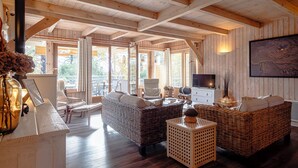 A wooden interior with wicker furniture, a fireplace, and a television. - Charming all-wood villa with heated pool -4 bedrooms -3 bathrooms (Biscarrosse)