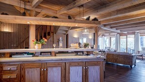A spacious kitchen with wooden cabinetry, a large island, and a dining area with a wicker sofa. - Charming all-wood villa with heated pool -4 bedrooms -3 bathrooms (Biscarrosse)
