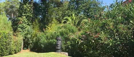 A well-maintained garden with a grassy lawn, various shrubs, and a prominent tree.