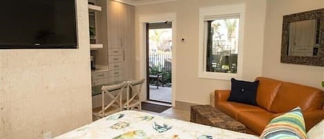 A bedroom with a bed, a sofa, a TV, and a window.