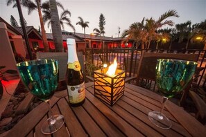 A wooden table with two green glass wine glasses, a bottle of Martini, and a lit candle in a square lantern. - The Rod and Reel Resort-Suite 5 (Anna Maria)