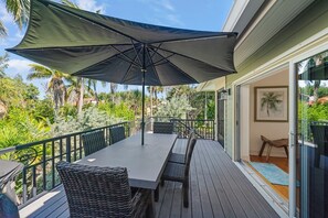 Eine Terrasse mit Tisch und Stühlen, umgeben von einem Geländer, mit Blick auf einen üppigen Garten.