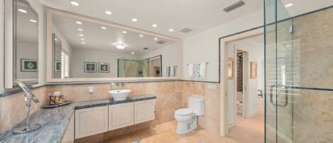 A modern bathroom with a large mirror, a sink, a toilet, and a shower area.