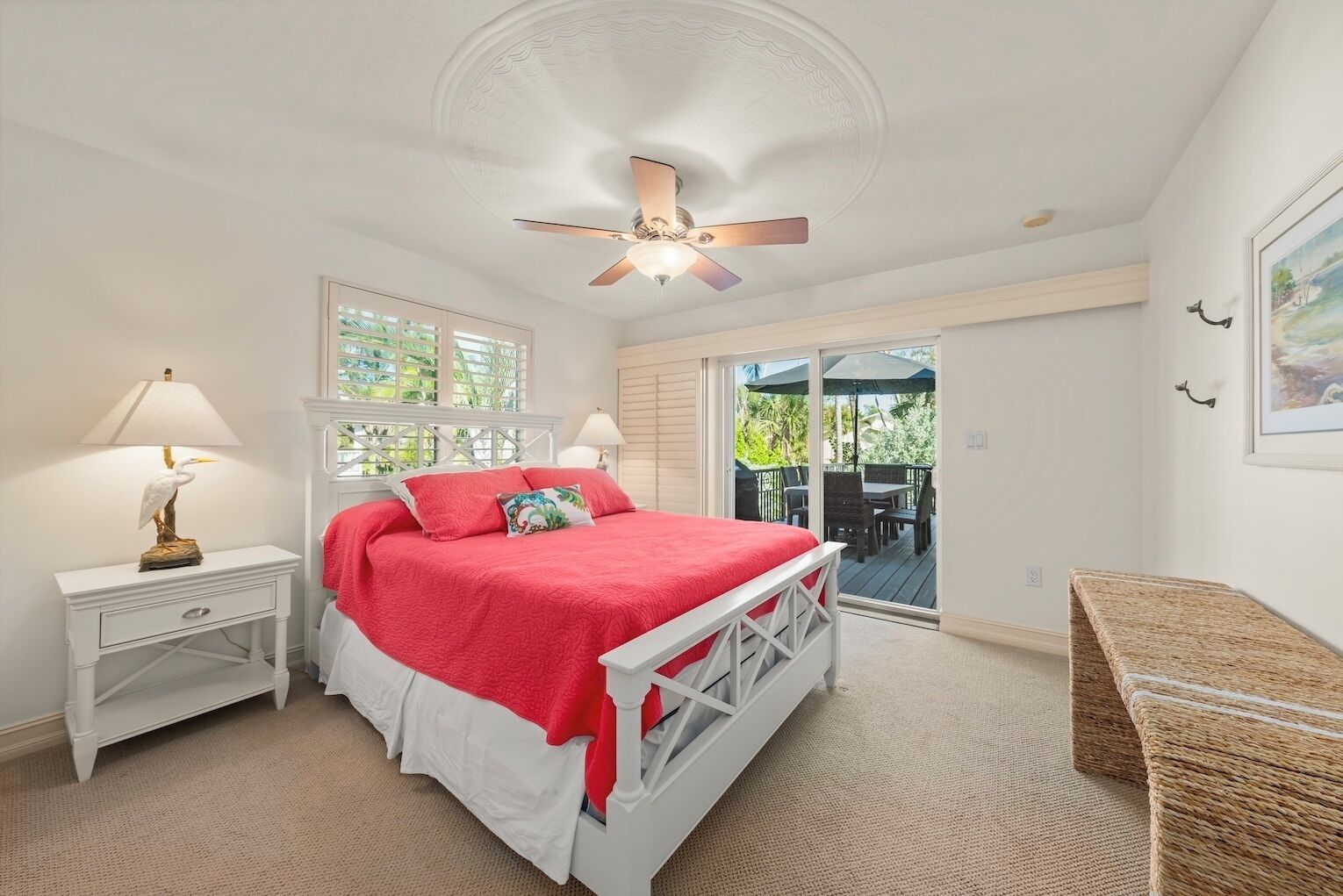 Un dormitorio con cama, mesitas de noche, ventilador de techo, ventana y vistas al exterior.