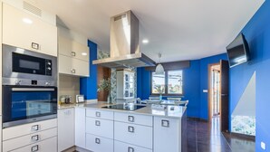 Cocina moderna con armarios blancos, electrodomésticos de acero inoxidable y una isla central.