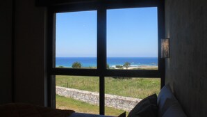 Una habitación con un amplio ventanal que ofrece vistas al mar y una pared de piedra.