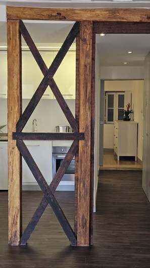 A modern kitchen with a central island, wooden beams, and a dark floor. - Historic Lisbon Alfama Apartament (Lisbon)