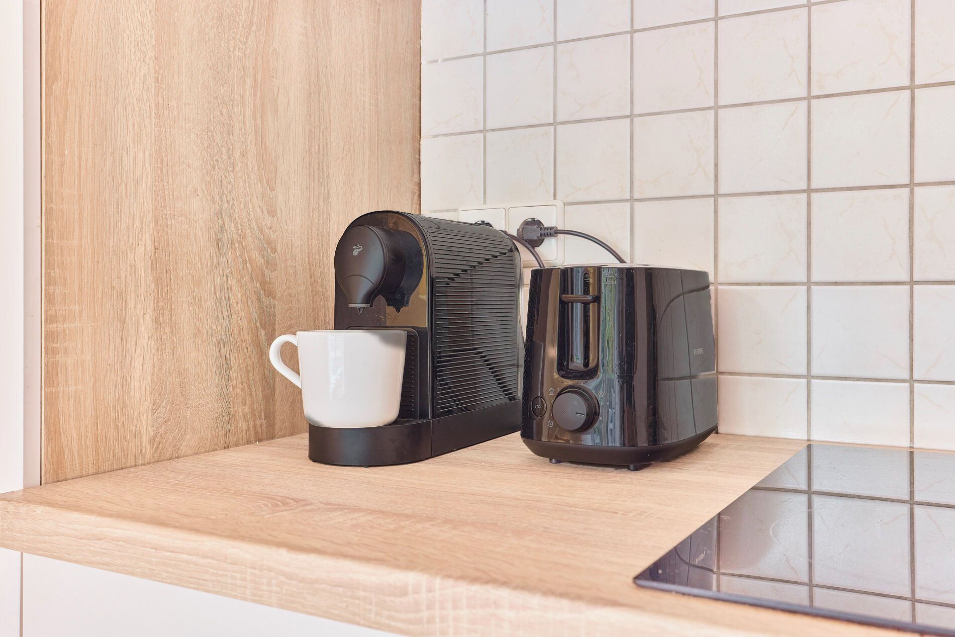 Een koffiezetapparaat met een kopje op een houten aanrecht.
