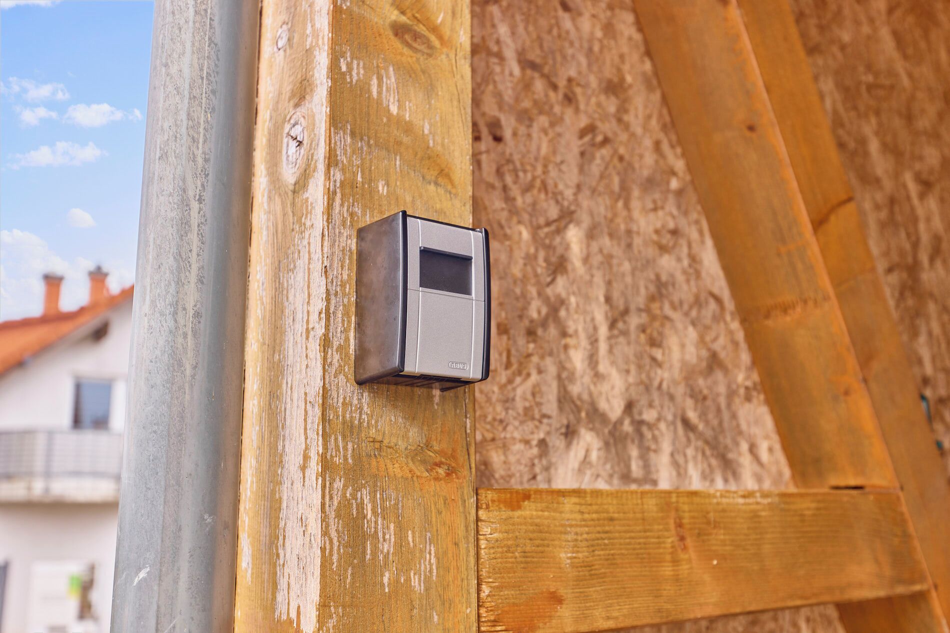 A close-up of a wooden door with a small, square, metallic object attached to it.
