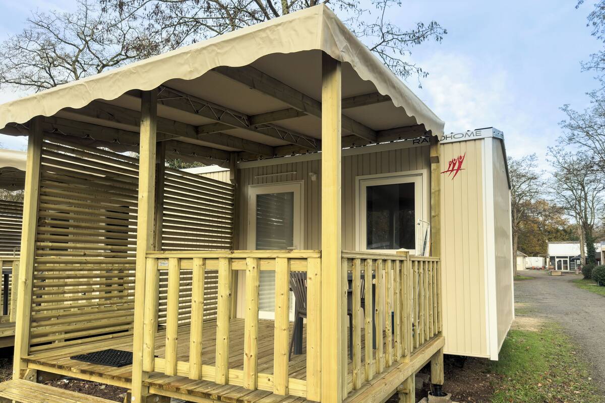 A wooden RV with a covered porch and a small attached building labeled "RAH HOME".