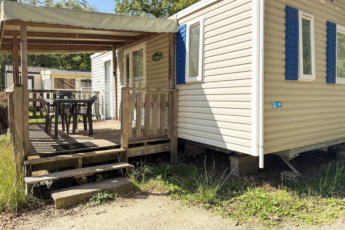 A mobile home with a porch, a table, and chairs.