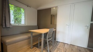 A room with a wooden floor, a bench, a table with a chair, and a white door. - Domaine Des Acacias Tours (La Ville-aux-Dames)