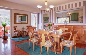 Un coin repas avec une table en bois, six chaises et un lustre.