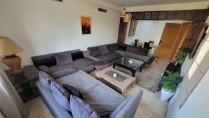Ein modernes Wohnzimmer mit einem Ecksofa, einem Couchtisch und einer Lampe.