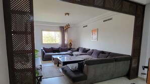 Ein modernes Wohnzimmer mit einer großen Eckcouch, einem Couchtisch und einem gemusterten Teppich.