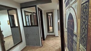 A hallway with mirrors, a tiled floor, and a decorative wall. - Apartment Le grand jardin (Marrakech)