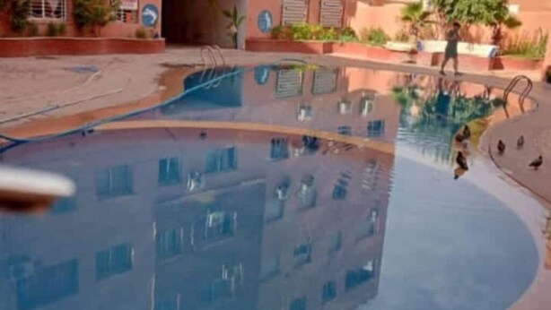 A swimming pool with a building reflected in the water. - Apartment Le grand jardin (Marrakech)