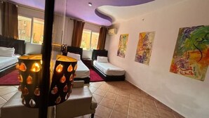 A hotel room with a curved ceiling, a bed with a red blanket, a bedside table with a lamp, and artwork on the walls. - Apartment Le grand jardin (Marrakech)