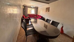 A conference room with a long table, black chairs, and a red sofa in the background. - Apartment Le grand jardin (Marrakech)