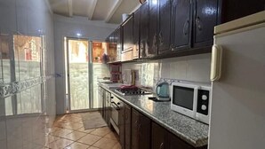 A kitchen with dark cabinets, a microwave, and a stove. - Apartment Le grand jardin (Marrakech)