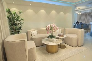 A modern living room with a beige sofa, a round coffee table, and a potted plant. - LD House: Luxury Near the U.S. Embassy (Santo Domingo)