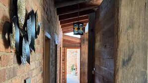 A narrow hallway with brick walls, wooden beams, and a tiled floor. - Country Homestead in Avenel (Avenel)