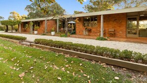 A modern brick building with a covered outdoor seating area, a gravel pathway, and a well-maintained lawn. - Country Homestead in Avenel (Avenel)