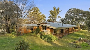A house with a covered patio, a lawn, and surrounding trees. - Country Homestead in Avenel (Avenel)