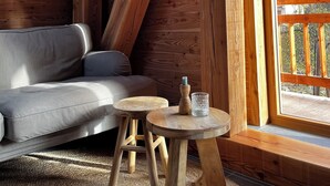 Ein Holzinnenraum mit einer Couch, zwei Hocker und einem Tisch mit Kerze und Glas.