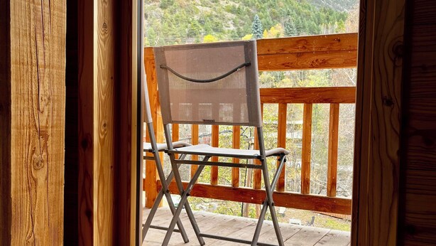 Eine Holzterrasse mit einem Klappstuhl und Blick auf einen Berg.