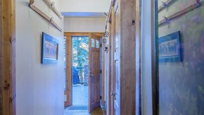 Un couloir avec des portes en bois, un tableau encadré au mur et une vue sur l’extérieur.