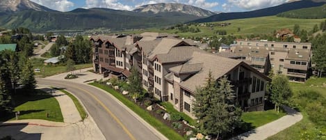 A multi-story hotel with a central courtyard, surrounded by mountains and greenery.