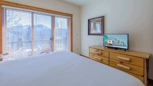 Une chambre à coucher avec un grand lit, une commode en bois et un téléviseur posé sur un meuble en bois.