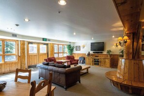 A spacious living area with a large sofa, chairs, a wooden coffee table, a television, and a wooden cabinet. - Black Bear Cabin, shared hot tub, walk to slopes! (Crested Butte)
